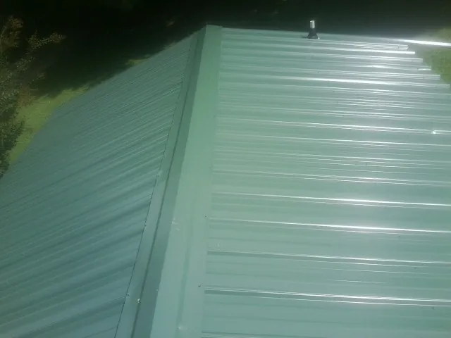 New green metal panels meeting at the ridge of a roof — Flat Roof Repair work by our crew in Waterloo